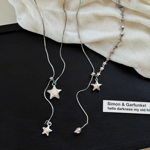 Detail of silver asymmetrical star necklaces with snake chain and tassel on black base
