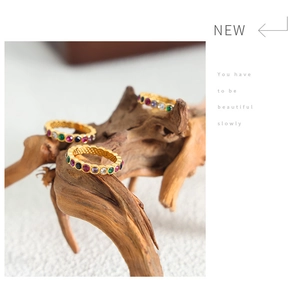 Macro detail of gold-plated rings featuring colorful zircons and honeycomb cutouts