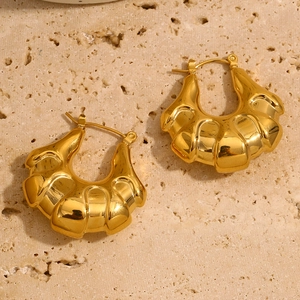Detail of 18K gold plated hollow croissant hoop earrings on a light textured stone background