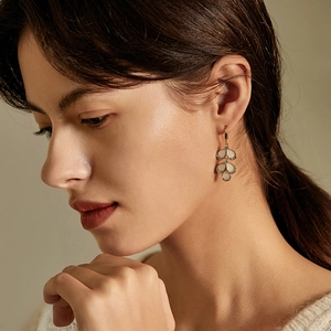 Elegant gold leaf earrings with opal stones and pave diamonds worn by a model