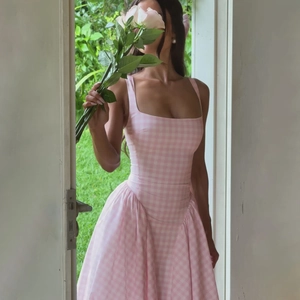 Detail of a French style pink plaid dress with waist cinching and square neckline