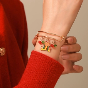 Close-up of a festive Christmas charm bracelet with gold coil and holiday pendants