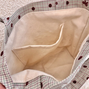 Detail view of canvas lunch bag interior featuring an inner pocket and plaid dot pattern