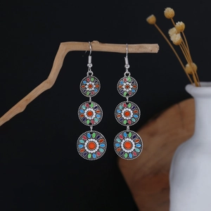 Close-up of Bohemian tiered enamel beaded earrings hanging on a natural wooden branch