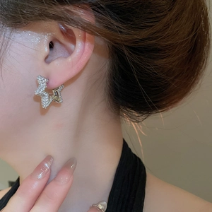 Close-up of a silver star-shaped earring with sparkling cubic zirconia on model ear