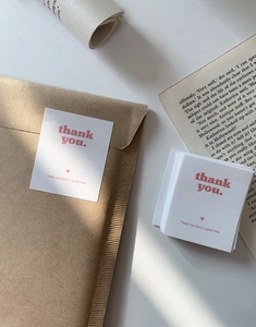 Close-up of minimalist white and pink Thank You cards on kraft envelopes for gift packaging