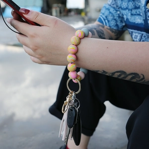 Outdoor close-up of colorful silicone bead bracelet keychain with tassel on a woman's wrist
