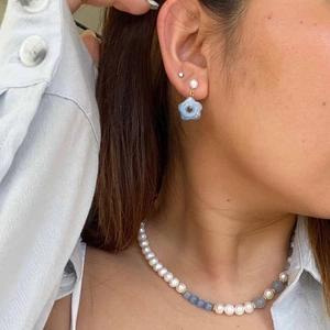 Close-up of glacier blue beads and white pearl necklace with floral drop earrings