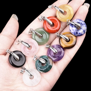 Variety of assorted crystal donut pendants with silver clasps on a dark background