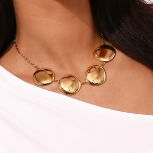 Detail showing high-polish gold textured round disc pendants on an 18K plated necklace