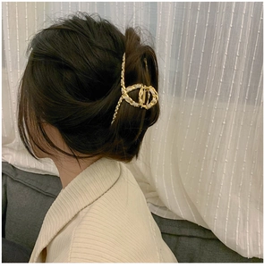 Detail of woven white ribbon and gold metal hair claw clip worn in a messy bun hairstyle