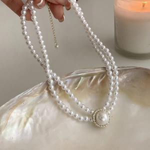 Détail du collier de perles double couche avec pendentif serti de strass et chaîne dorée