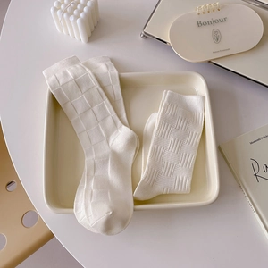 Creamy white vertical striped crew socks in a minimalist aesthetic home setting