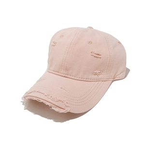 Detailed view of pink distressed baseball cap showing ripped cotton fabric and vintage holes