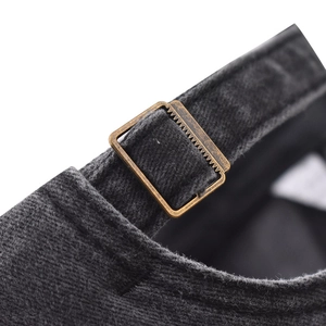 Detail of adjustable bronze metal buckle on dark grey corduroy baseball cap