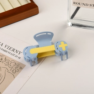 Detailed view of a light blue acetate hair claw clip with yellow stripes on a desk