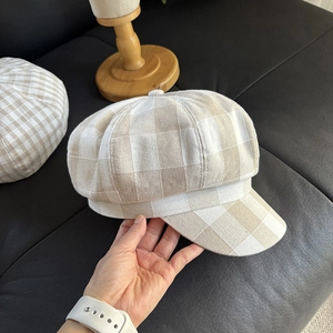 Detail of linen plaid newsboy cap showing beige textured fabric and stitching