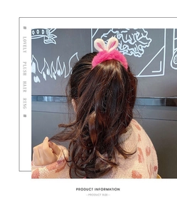 Close-up of pink plush bunny ear scrunchie worn on a ponytail for girls