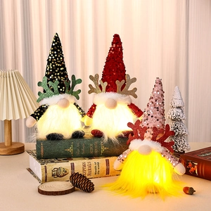 Trois gnomes de Noël à paillettes avec lumières LED posés sur des livres de décoration