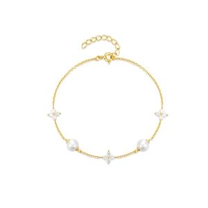 Elegant gold leaf and pearl bracelet with sparkling stones on a minimalist white base