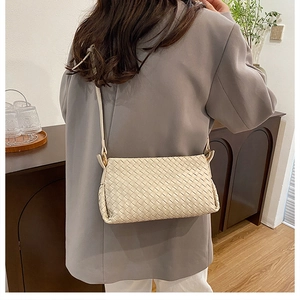Détail d'un sac bandoulière tissé crème minimaliste avec bandoulière et finitions dorées