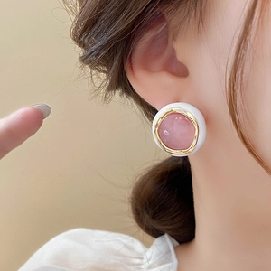 Detailed view of elegant gold-plated round earrings with pink opal stone on a model