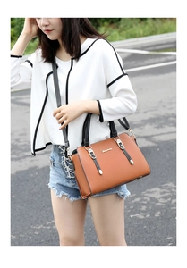 Outdoor shot of a brown three-piece handbag set with black straps and metal accents