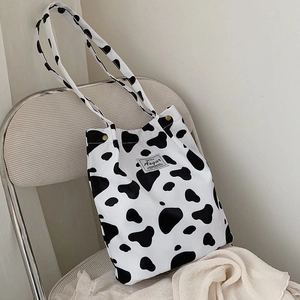 Detail of Augur canvas tote bag featuring black and white cow print and brand label