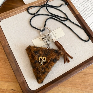 Macro shot of brown plush triangle pendant with gold heart heart and fringe tassel
