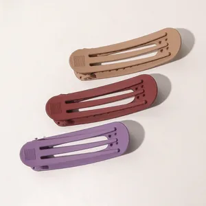 Close-up of three matte colorful hair clips in brown, red, and purple with hollow stripe design