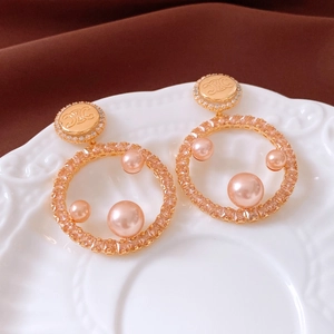 Detailed shot of 18K gold plated pearl hoop earrings with crystal pavé and brand logo