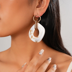 Detail of bohemian drop earrings with white and brown marble texture and gold metal ring