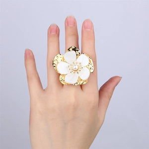 Detail of 18k gold plated ring featuring shell flower petals and a center pearl on model