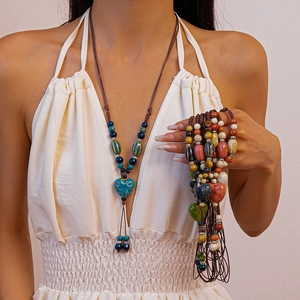 Détail de colliers en perles de céramique colorées avec pendentifs cœur style bohème