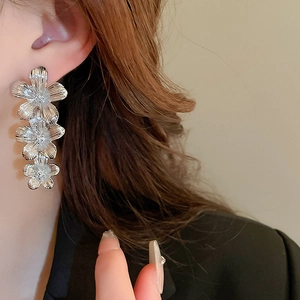 Detail of silver layered flower earrings with brushed metal texture worn by a model
