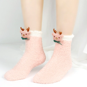 Nahaufnahme der rosa Plüsch-Korallenvlies-Socken mit Rentier-Puppe und grüner Schleife