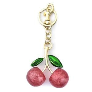 Sparkly red cherry keychain with gold metal clasp and green leaves on white background