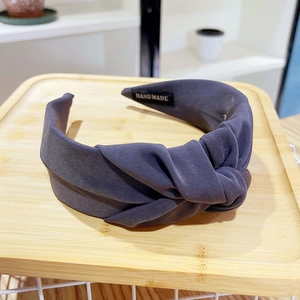 Detailed macro view of dark grey knitted wide knot headband with a handmade inner label