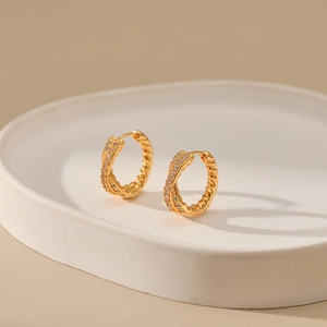 Close-up of twisted 18K gold-plated hoops featuring delicate white cubic zirconia micro-paving