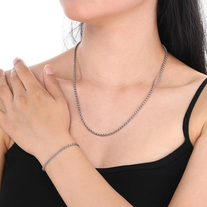 Detailed view of silver braided chain necklace and bracelet set worn by a model