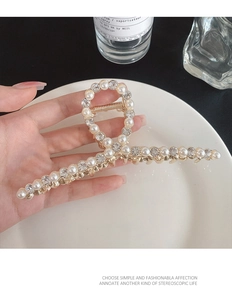 Détail d'une pince à cheveux dorée ornée de perles et de strass étincelants