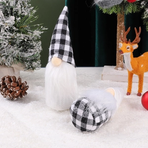 Close-up of black and white buffalo plaid gnome figurines in a snowy Christmas setting
