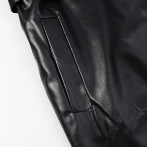 Close-up of side pocket stitching on black leather trench coat with glossy finish
