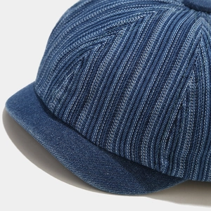 Detailed macro view of denim newsboy cap with decorative white V-shaped stitching