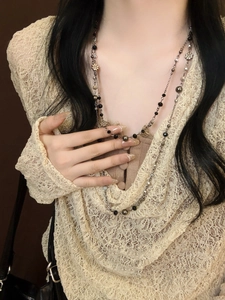Close-up of double-layer beaded necklace featuring black beads and metallic flower charms