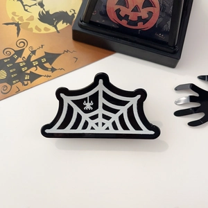 Vue détaillée d'une pince à cheveux motif toile d'araignée d'Halloween avec petite araignée