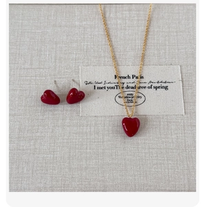Detail of red heart pendant necklace and earring set on textured fabric background