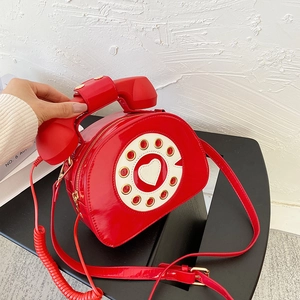 Detail of red patent leather telephone bag showing heart dial and handset handle