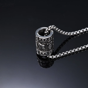 Retro stainless steel cylinder mantra pendant necklace with Buddhist carvings on dark background