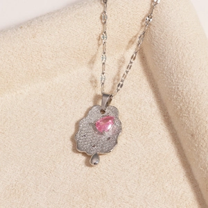 Detail of silver cloud-shaped pendant with pink zircon and teardrop dangle on beige fabric